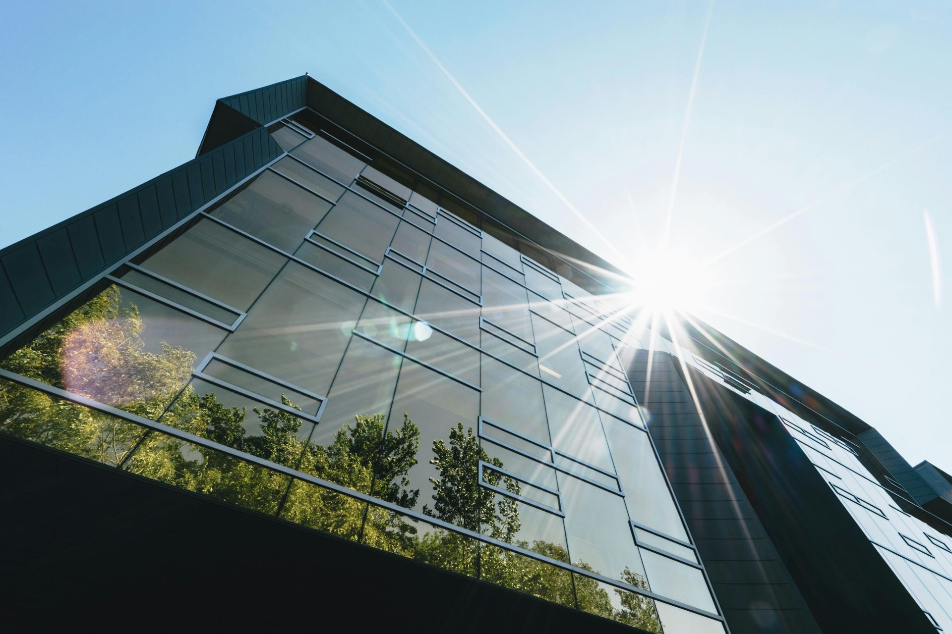 Low angle view of a modern skyscraper with reflections and sun flare, emphasizing contemporary architecture.